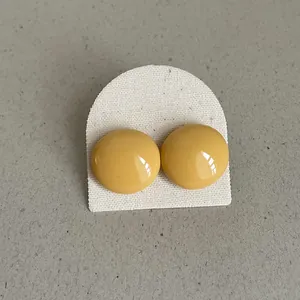 Close-up of vibrant yellow bean-shaped drip oil stud earrings on a display card