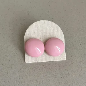 Detailed close-up view of pink round dome stud earrings on an off-white display card