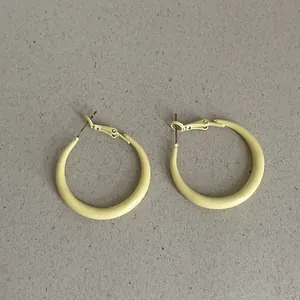 Macro detail showing the bright yellow oil-dripping matte finish of these hoop earrings