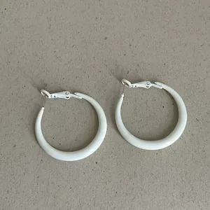 Detailed view of trendy thick white enamel hoop earrings with smooth glossy finish