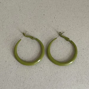 Detail view of olive green geometric hoop earrings with a smooth drip oil finish