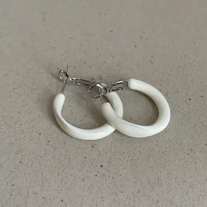 Close-up view of elegant white enamel hoop earrings with silver-tone metal closure.