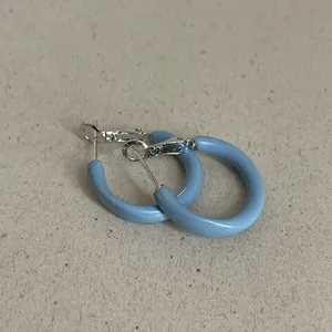 Close-up of light blue oil-dripped geometric hoop earrings with silver-tone findings
