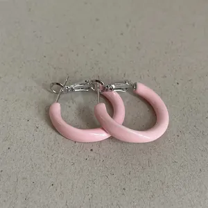 Close-up of pink enamel hoop earrings with a smooth, glossy dopamine-style finish