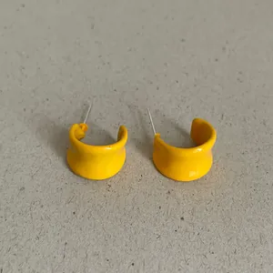 Close-up macro view of vibrant bright yellow enamel geometric C-shaped stud earrings