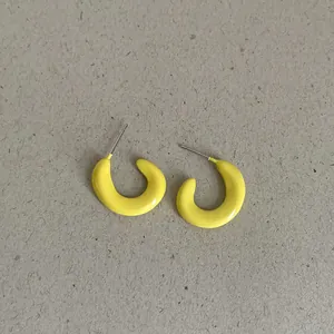 Close-up of bright yellow bean-shaped geometric earrings on a textured background.