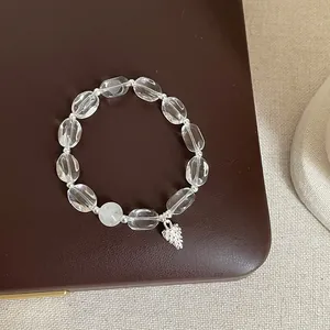 Gros plan d'un bracelet en cristal blanc avec un pendentif pomme de pin en argent.