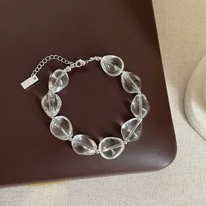 Gros plan d'un bracelet en cristal transparent avec chaîne argentée sur cuir marron.