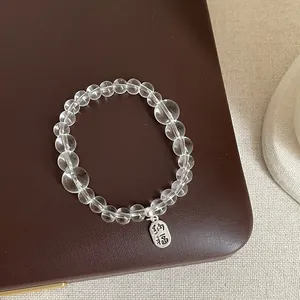 Détail d'un bracelet de perles en cristal clair avec une breloque argentée de bénédiction Nafu