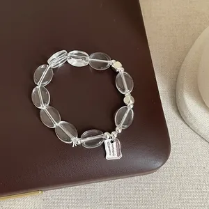 Gros plan d'un bracelet en perles de cristal avec breloque en argent sur fond cuir
