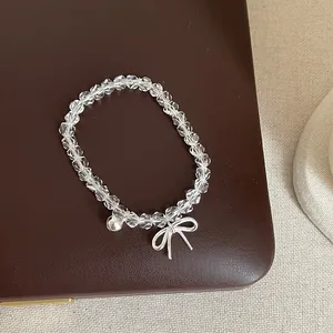 Gros plan d'un bracelet en perles de cristal blanc avec nœud et cloche en argent