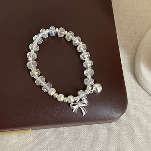 Vue rapprochée d'un bracelet en cristal avec un nœud argenté et une petite clochette