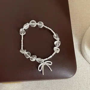 Gros plan détaillé d'un bracelet en quartz irrégulier clair avec un charm noeud argenté