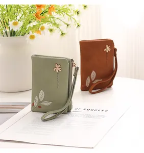 Minimalist floral embossed short wallets in green and brown displayed on an open magazine