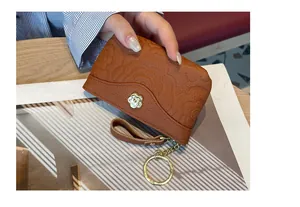 Vue détaillée du porte-monnaie en cuir gaufré avec motif camélia et porte-clés doré