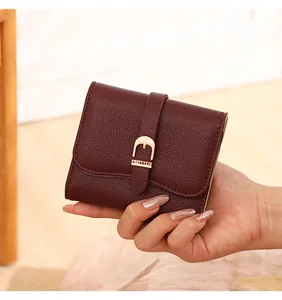 Detailed view of a burgundy pebble-grain short wallet featuring a stylish gold buckle strap.
