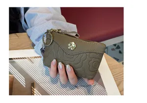Gros plan d'un mini porte-monnaie en cuir marron avec motif floral et breloque dorée