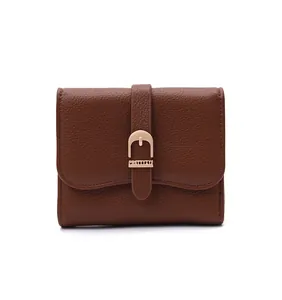 Detail of brown leather women's short wallet with decorative gold belt buckle.