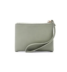Close-up detail of a minimalist sage green faux leather coin pouch with a wrist strap