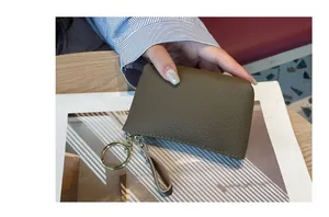 Gros plan du petit porte-monnaie en cuir vert olive avec anneau de clé doré et fermeture