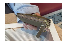 Gros plan d'un mini porte-monnaie en cuir kaki avec porte-clés doré et fermeture