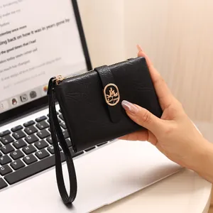 Primer plano de cartera corta negra para mujer con textura craquelada y logo dorado