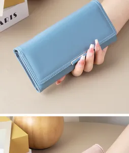 Elegant long blue wallet with smooth leather texture held by hand in a modern setting