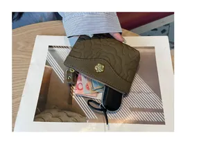 Vue détaillée d'un mini porte-monnaie en cuir gaufré avec emblème floral doré