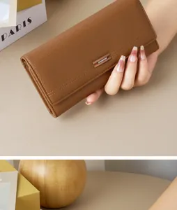 Close-up detail of a brown textured leather long wallet for women being held in hand