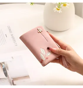 Detailed close-up of a pink short wallet with floral print and a matching wrist strap