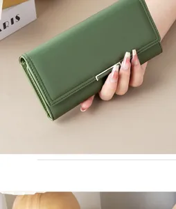 Close-up detail of a minimalist green textured leather long wallet held by hand