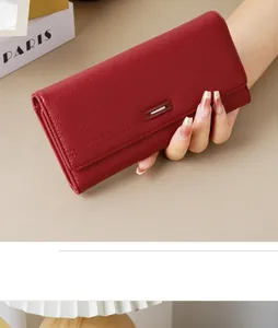Close-up detail of a red pebbled leather long wallet with a stylish metal buckle decoration