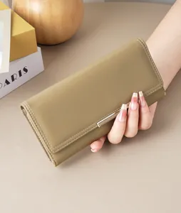 Close-up of a khaki minimalist long wallet held in hand with flap design.