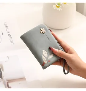 Macro view of fresh floral print and metal flower charm on women's blue wristlet wallet