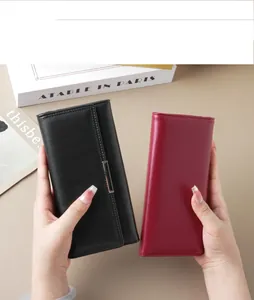 Close-up of elegant black and burgundy long wallets held by hands in a studio setting.