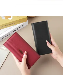 Showcasing the red and black long leather wallets held in hands to display size and texture.