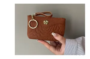Détail du porte-monnaie en cuir marron avec motif floral et porte-clés doré