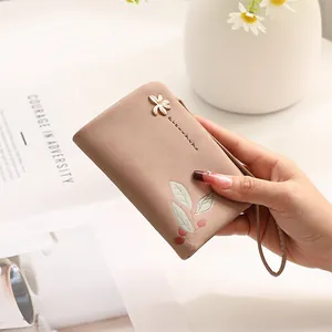 Detailed view of elegant pink wallet with leaf prints and floral charm holder