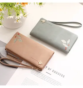 Detail shot of long PU leather wallets featuring elegant leaf prints and flower charms