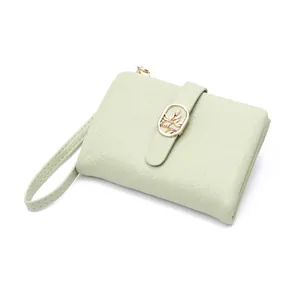 Detalle de una cartera corta verde matcha con textura craquelada y cierre dorado