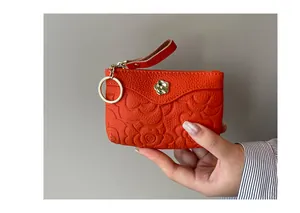 Vue détaillée du porte-monnaie en cuir orange avec gaufrage camélia et fermoir fleur