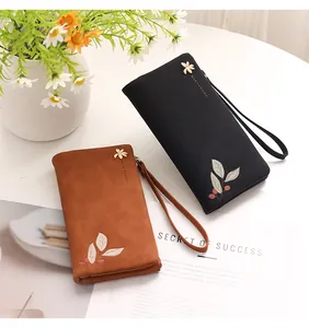 Close-up of black and brown PU leather wallets with leaf embroidery and wristlets