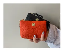 Gros plan de mini porte-monnaie en cuir avec motif camélia embossé et détails dorés.