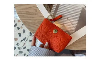 Gros plan d'un porte-monnaie en cuir gaufré orange avec motif floral et fermoir doré