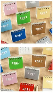Close-up view of multiple colorful 2027 mini desk calendars on a natural wood background