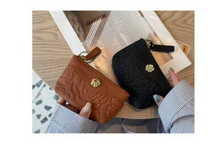 Détail de porte-monnaie en cuir gaufré marron et noir avec porte-clés et fleurs
