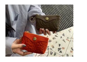 Détail de mini-porte-monnaie en cuir gaufré orange et marron avec fleur.