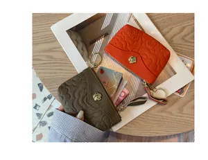 Gros plan d'un mini porte-monnaie en cuir avec relief camélia et porte-clés doré élégant