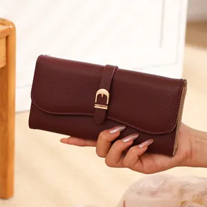 Close-up of elegant burgundy long wallet with gold buckle detail and lychee texture