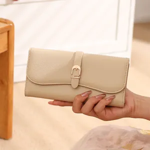 Close-up view of a fashionable beige long leather wallet for women held in a hand